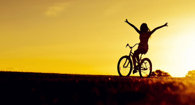 Girl on bicycle at sunset